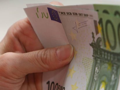 Una persona sostiene billetes de 100 euros. 