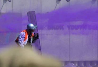 Un manifestante se protege con un escudo de los chorros de agua lanzada a presión por la Policía durante los enfrentamientos.