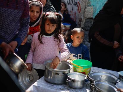 Unos niños palestinos esperan a recibir comida de una organización benéfica este martes, mientras hay  escasez de alimentos, en Rafah.