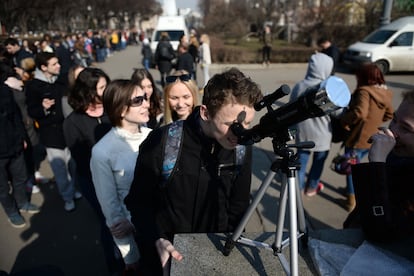 Um grupo de pessoas face fila para olhar ou telescópio em Moscou (Rússia).