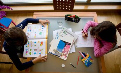 Unos niños hacen deberes con libros en gallego.