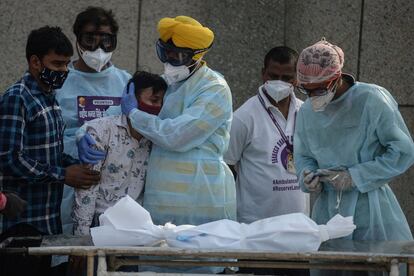 Un voluntario consuela a un familiar de un niño que murió por la covid en un crematorio de Nueva Delhi. Las muertes por coronavirus en la India superaron este jueves las 4.000 por segundo día consecutivo y los contagios aumentaron hasta los 360.000 en la última jornada.