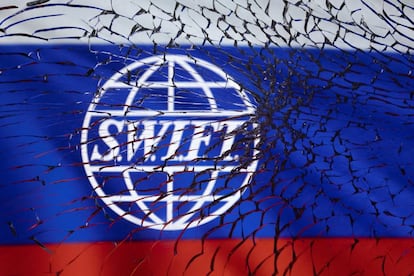 Illustration shows SWIFT logo and Russian flag through broken glass