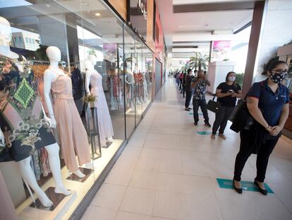 Decenas de personas con mascarillas haciendo fila, este miércoles, en un centro comercial de Brasilia.