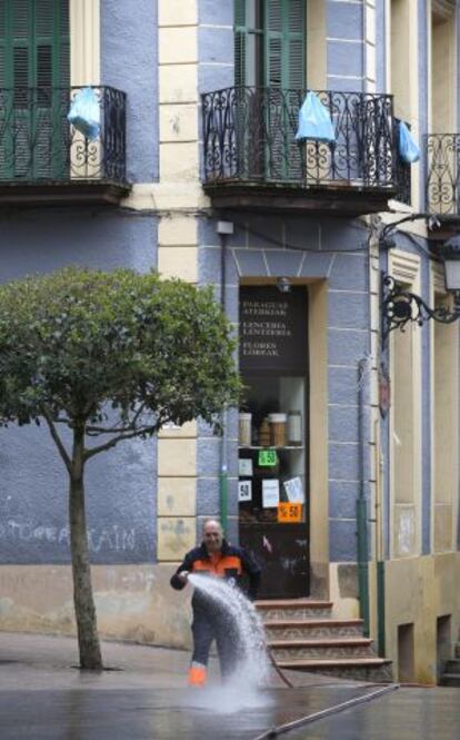 Un operario municipal riega las calles de Ordizia. Al fondo, bolsas de basura en los balcones contra el puerta a puerta.