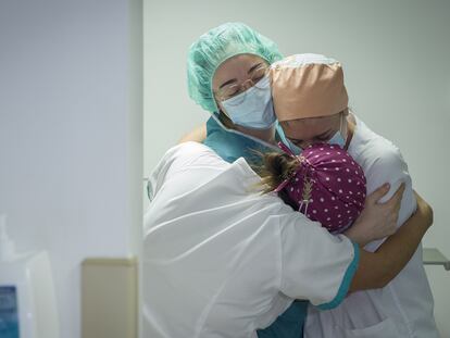 Tres enfermeras se abrazan por el traslado a planta del último paciente ingresado en la Unidad de Cuidados Intensivos con coronavirus del hospital Quirónsalud Sagrado Corazón de Sevilla.