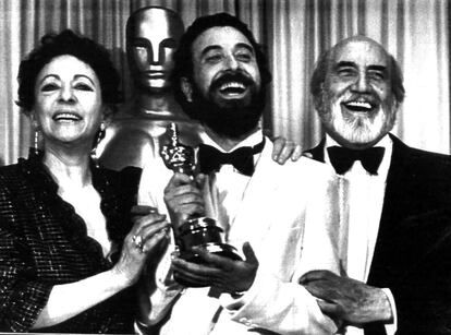 El director de cine José Luis Garci sonríe mientras sostiene el Oscar a la mejor película de habla no inglesa por 'Volver a empezar', en la noche del 12 de abril de 1983, junto a la actriz Encarna Paso (izquierda) y el actor Antonio Ferrandis.