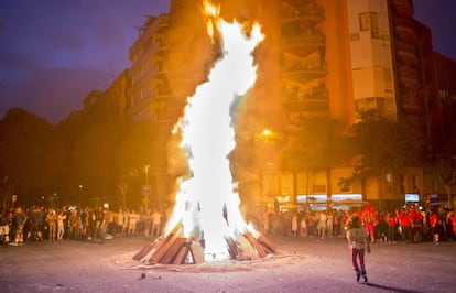 Un grupo de personas disfrutando de la gran hoguera instalada entre las calles Viladomat y Floridablanca de Barcelona