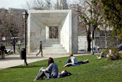 Varias personas toman el sol al lado del monumento a la Constitución, junto a la Castellana.