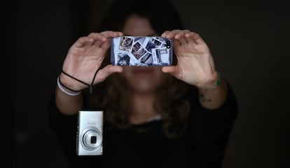 Un joven haciendo fotos con su tel&eacute;fono m&oacute;vil (iPhone) y colgando de su mu&ntilde;eca una c&aacute;mara fotogr&aacute;fica compacta.    