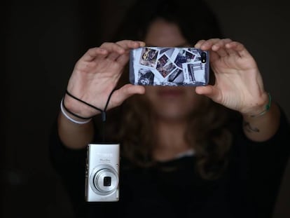 Un joven haciendo fotos con su tel&eacute;fono m&oacute;vil (iPhone) y colgando de su mu&ntilde;eca una c&aacute;mara fotogr&aacute;fica compacta.    