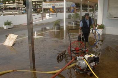 Las fuertes lluvias caídas en Málaga han provocado inundaciones en la localidad de Marbella. En la imagen, un hombre intenta sacar el agua de una zona cercana al puerto deportivo.