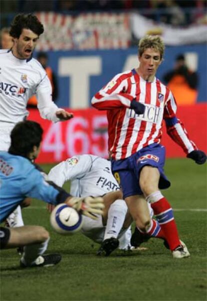 Fernando Torres, acosado por dos rivales, intenta rematar ante Riesgo.