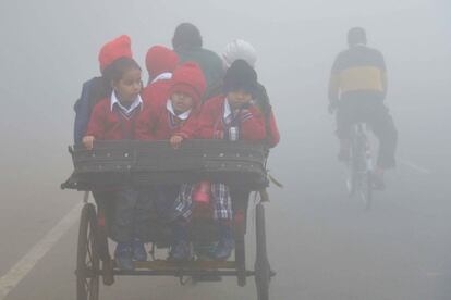 Niños indios camino de la escuela en un ciclo-rickshaw. Es la forma que tienen de asistir al colegio las mañanas frías de imvierno en Amritsar, India.