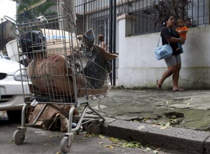 Una mujer y un niño pasan ante un cadáver metido en un carro de la compra, el pasado martes en la favela Morro dos Macacos.