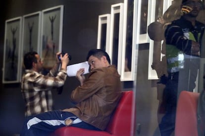 Gao Ping, wearing a brown jacket, looks away as police raid his Madrid art gallery on Tuesday.