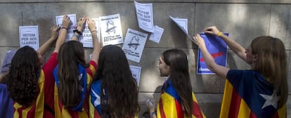 Varias estudiantes pegan carteles en la pared de la Universidad de Barcelona durante el inicio de la &quot;Marat&oacute;n por la democracia&quot;.