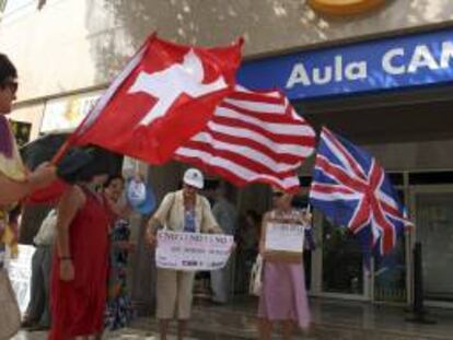 Miembros de la Plataforma de Afectados por las Cuotas Participativas de la Caja de Ahorros del Mediterráneo (CAM) se manifiestan a las puertas del Aula Cultural de la CAM, en Alicante. EFE/Archivo