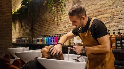 Un estilista atiende a una clienta en el salón de peluquería Alma, en Barcelona.