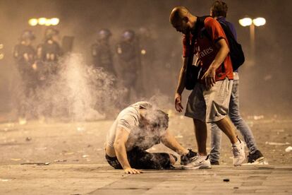 Na imagem, um homem cai ao chão após inalar gases lacrimogêneos durante os confrontos dos torcedores com a polícia de Paris.