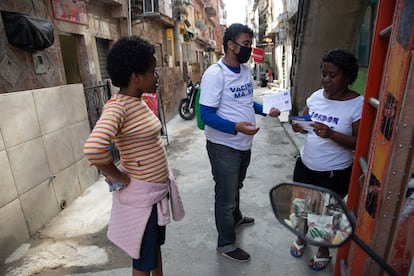 Voluntário entrega panfletos sobre a vacinação contra covid-19 para os moradores da Maré.