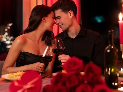 Una pareja a punto de besarse en una cena romántica con vino.
