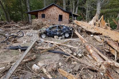 Un automóvil destruido se encuentra entre escombros frente a una casa que fue arrastrada varios cientos de pies por un arroyo después del huracán 'Helene', en Barnardsville.