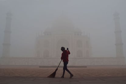Un hombre barre frente al Taj Mahal en medio de una densa niebla en Agra (La India).