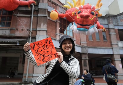 A woman holds a spring couplet with dragon patterns that she drew herself for the upcoming Lunar New Year celebrations at the Dihua street market in Taipei, Taiwan, Thursday, Feb. 8, 2024.