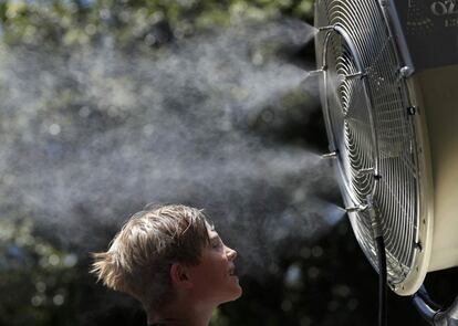 Un niño se refresca frente a un ventilador de nebulización en el partido abierto de tenis en Melbourne (Australia).