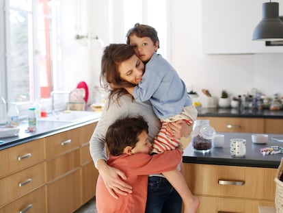 A mom hugging her sons in the kitchen