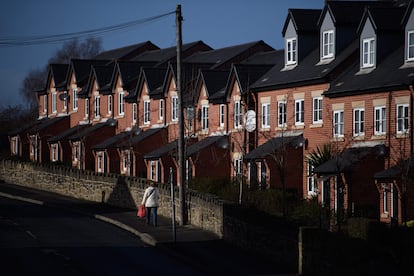 Una mujer camina frente a una hilera de casas en el centro de la ciudad de Wrexham.