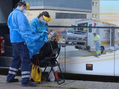 Unos enfermeros realizan un test a una mujer en el exterior de una de las doce unidades móviles que la Junta de Castilla y León ha contratado para hacer test de antígenos a la población que tenga síntomas durante todo el mes de enero, este martes en Valladolid.