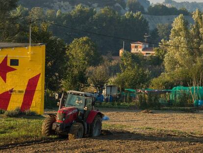 Un agricultor con un tractor ante una fachada que tiene pintada una &#039;estelada&#039;