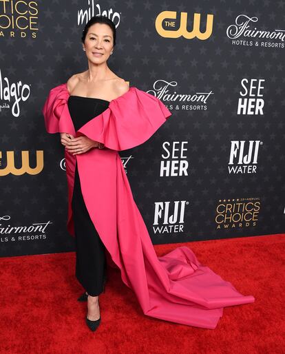 Michelle Yeoh, con vestio negro y capa fucsia de Carolina Herrera.