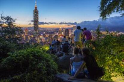 Turistas contemplando la torre Taipei 101, al atarceder.