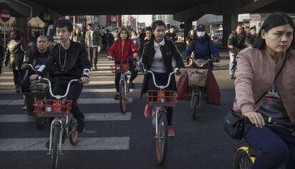 Ciudadanos chinos conducen sus bicicletas en una calle de Pekín (China), el 27 de marzo de 2017.