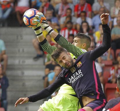 El portero del Sporting de Gijón Iván Cuéllar (d) y el defensa del FC Barcelona Gerard Piqué (d).