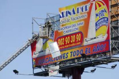 Miembros de los bomberos aseguran una valla publicitaria dañada por el viento eb la localidad madrileña de Torrejón de Ardoz. EFE/Archivo