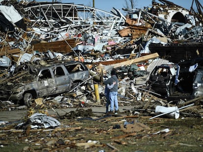 People embrace as tornado damage is seen after extreme weather hit the region December 12, 2021, in Mayfield, Kentucky. - Dozens of devastating tornadoes roared through five US states overnight, leaving more than 80 people dead Saturday in what President Joe Biden said was "one of the largest" storm outbreaks in history. (Photo by Brendan Smialowski / AFP)