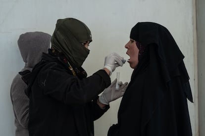 An SDF member collecting DNA samples from a woman at the section for Iraqi nationals inside Al-Hol camp. 