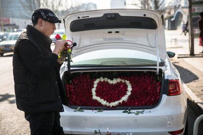 Un hombre decora el maletero de un coche con rosas cerca de un mercado de flores en la víspera del Día de San Valentín en Pekín (China), el 13 de febrero de 2018.