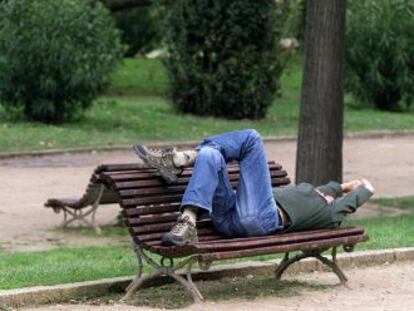 Un hombre se echa la siesta en un parque de Barcelona.