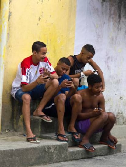 J&oacute;venes consultan sus m&oacute;viles en el barrio de Vig&aacute;rio Geral, en R&iacute;o de Janeiro. 