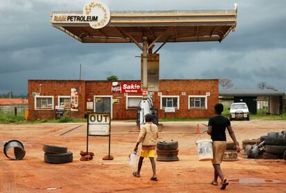 Dos niños se dirigen a una gasolinera que permanece cerrada debido a los conflictos que se han producido en Harare.