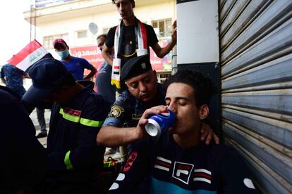 En Samawah, otra ciudad del sur del país, la multitud ha incendiado las sedes de varios partidos islamistas chiíes asociados con Irán. En la imagen, un policía da de beber a un herido durante las protestas en Bagdad (Iraq).