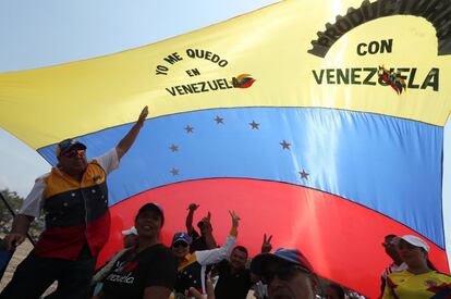 Un grupo de personas se cubre con una gran bandera venezolana durante el 'Venezuela Aid Live' el viernes, en el puente fronterizo de Tienditas, en Cúcuta (Colombia). El concierto comenzó en el lado colombiano del puente fronterizo de Tienditas con el himno nacional de Colombia y entre los aplausos de los miles de personas que acudieron a la cita.
