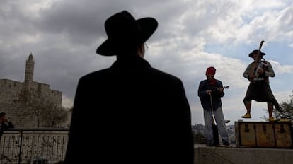 Un jud&iacute;o ultraortodoxo observa una actuaci&oacute;n musical callejera frente a la Torre de David en el casco antiguo de Jerusal&eacute;n.