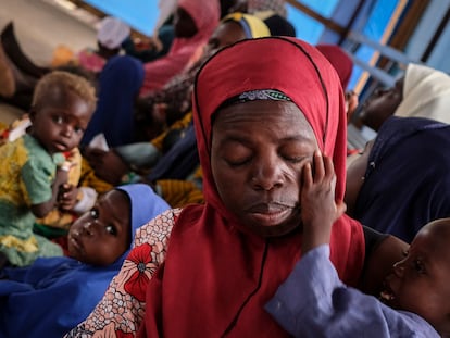 Una madre agotada con su hijo en el centro de educación nutricional para casos moderados de Aguié. Al fondo, el cabello de otro niño se ha aclarado, un síntoma habitual de la malnutrición.
