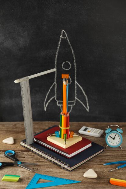 ESPECIAL FORMACIÓN Rocket from stationery on desk and background of chalkboard. Children imagination and creativity. Back to school